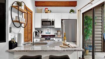 A modern kitchen with white cabinets, stainless steel appliances, and a central island with bar stools.