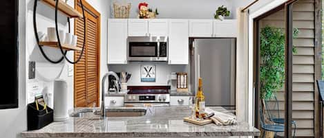 A modern kitchen with white cabinets, stainless steel appliances, and a central island with bar stools.