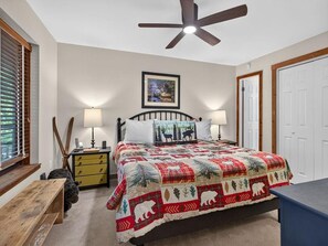 A bedroom with a bed, two bedside lamps, a ceiling fan, a window with blinds, a wooden bench, and a door. - Dobie 25 with Wintergreen Advantage (Wintergreen)