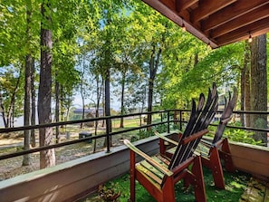 A wooden deck with two chairs, a railing, and a view of trees and a building in the background. - Dobie 25 with Wintergreen Advantage (Wintergreen)