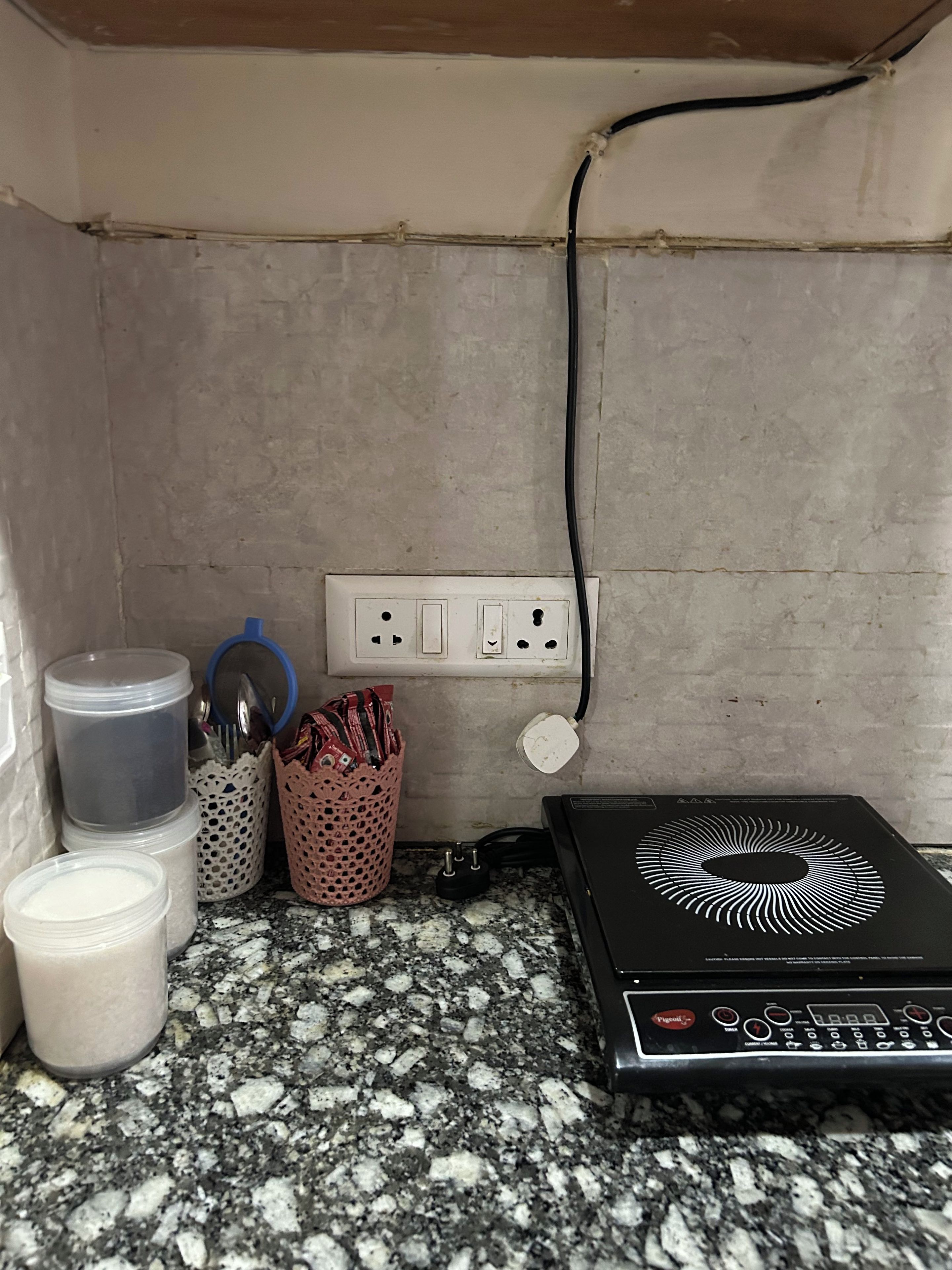 Eine Küchenarbeitsplatte mit Kaffeemaschine, einem Behälter und einer Mehrfachsteckdose.