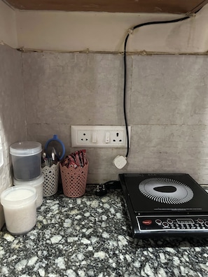 Un comptoir de cuisine avec une machine à café, un récipient et une multiprise.