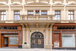 Une façade d’immeuble avec une entrée centrale, de grandes fenêtres et un balcon agrémenté de balustrades.