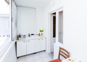 A small, white room with a window, a cabinet, a chair, and a table. - Apartment Vukoja - One-bedroom Apartment With Balcony (Dubrovnik)