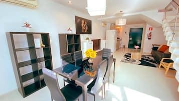 Un salon moderne comprenant un coin repas, un escalier et une cuisine.