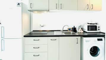 Cocina compacta con lavadora, microondas y refrigerador.
