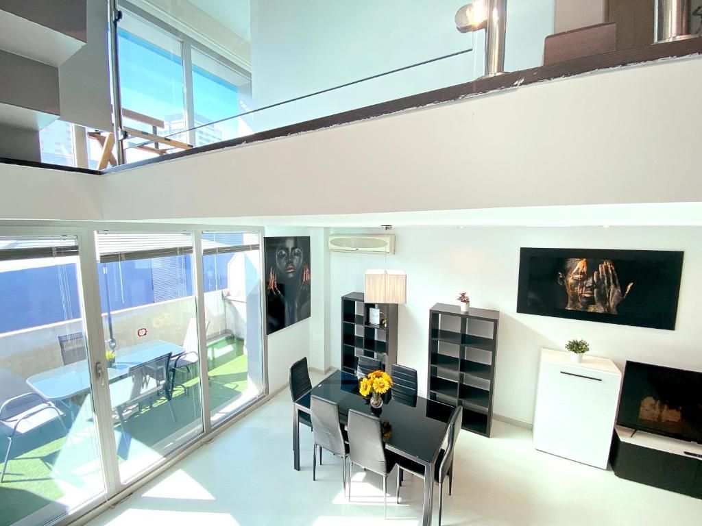 A modern interior with a dining area, a TV, and a balcony with a view.