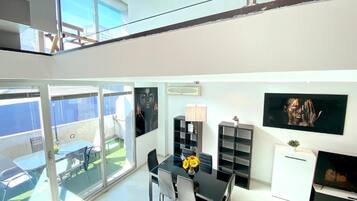 A modern interior with a dining area, a TV, and a balcony with a view.
