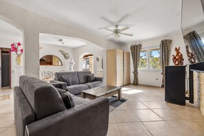 A living room with a grey sofa set, a wooden coffee table, and a ceiling fan. - La Treille de Saint-Marc by sur la mer (Camps-la-Source)