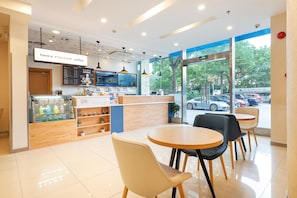 A modern coffee shop interior with a wooden counter, menu board, and seating area with tables and chairs. - Hanting Hotel Shanghai (Shanghai)