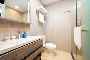 A modern bathroom with a wooden vanity, a toilet, and a glass shower enclosure. - Hanting Hotel Shanghai (Shanghai)