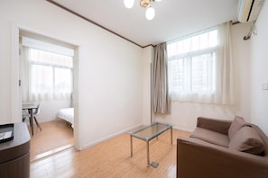 A modern living room with a glass coffee table, a sofa, and a dining area with a table and chairs. - Hanting Hotel Shanghai (Shanghai)