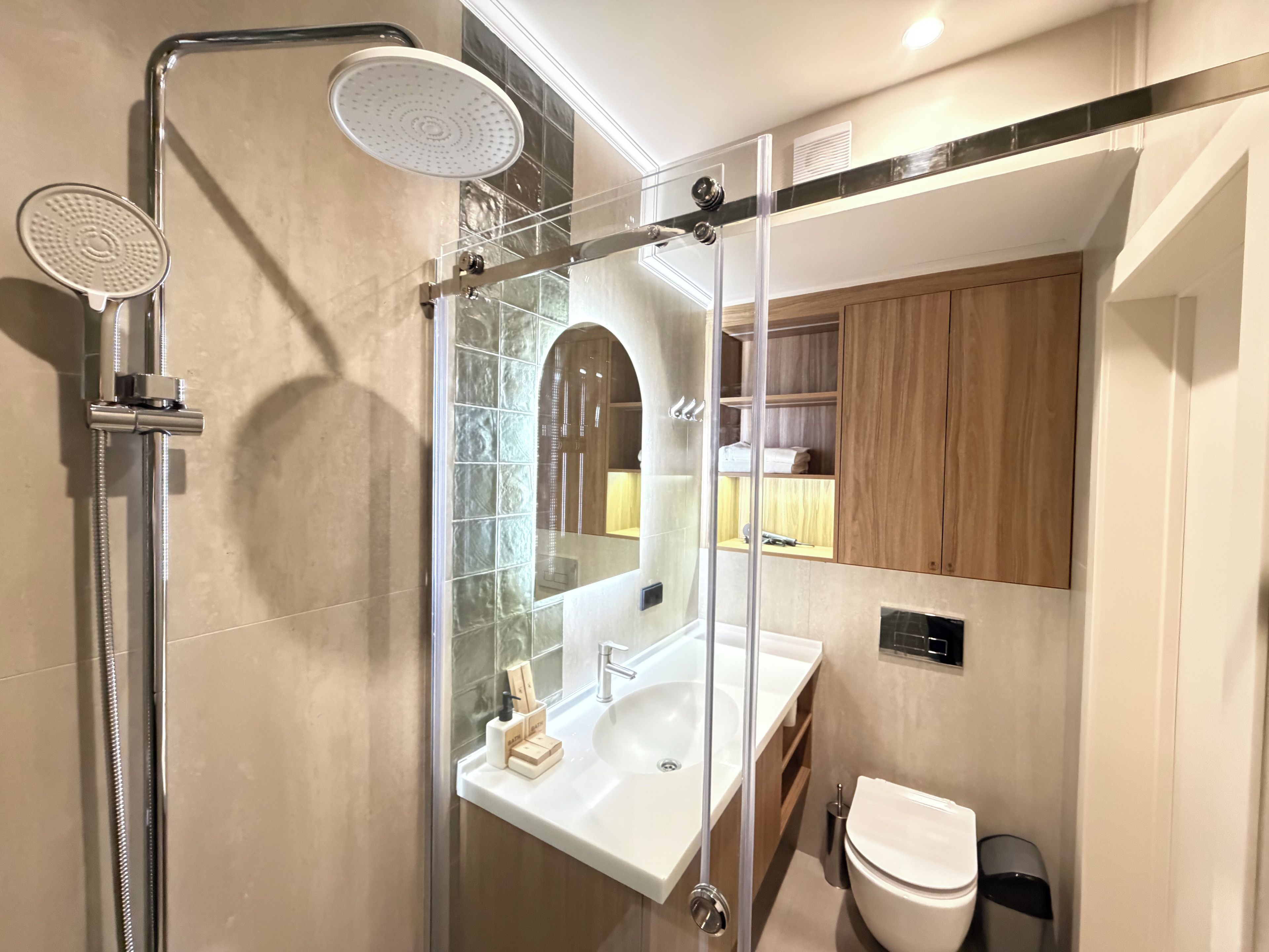 A modern bathroom with a glass-enclosed shower, a white sink, and a wooden vanity.