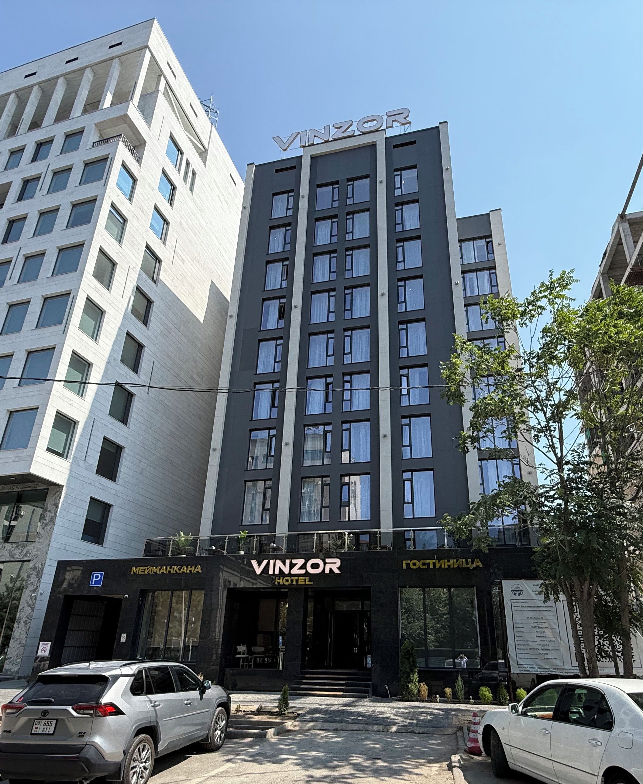 Un edificio moderno con un llamativo letrero de 'VINZOR HOTEL' en la entrada.
