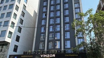 Un edificio moderno con un llamativo letrero de 'VINZOR HOTEL' en la entrada.