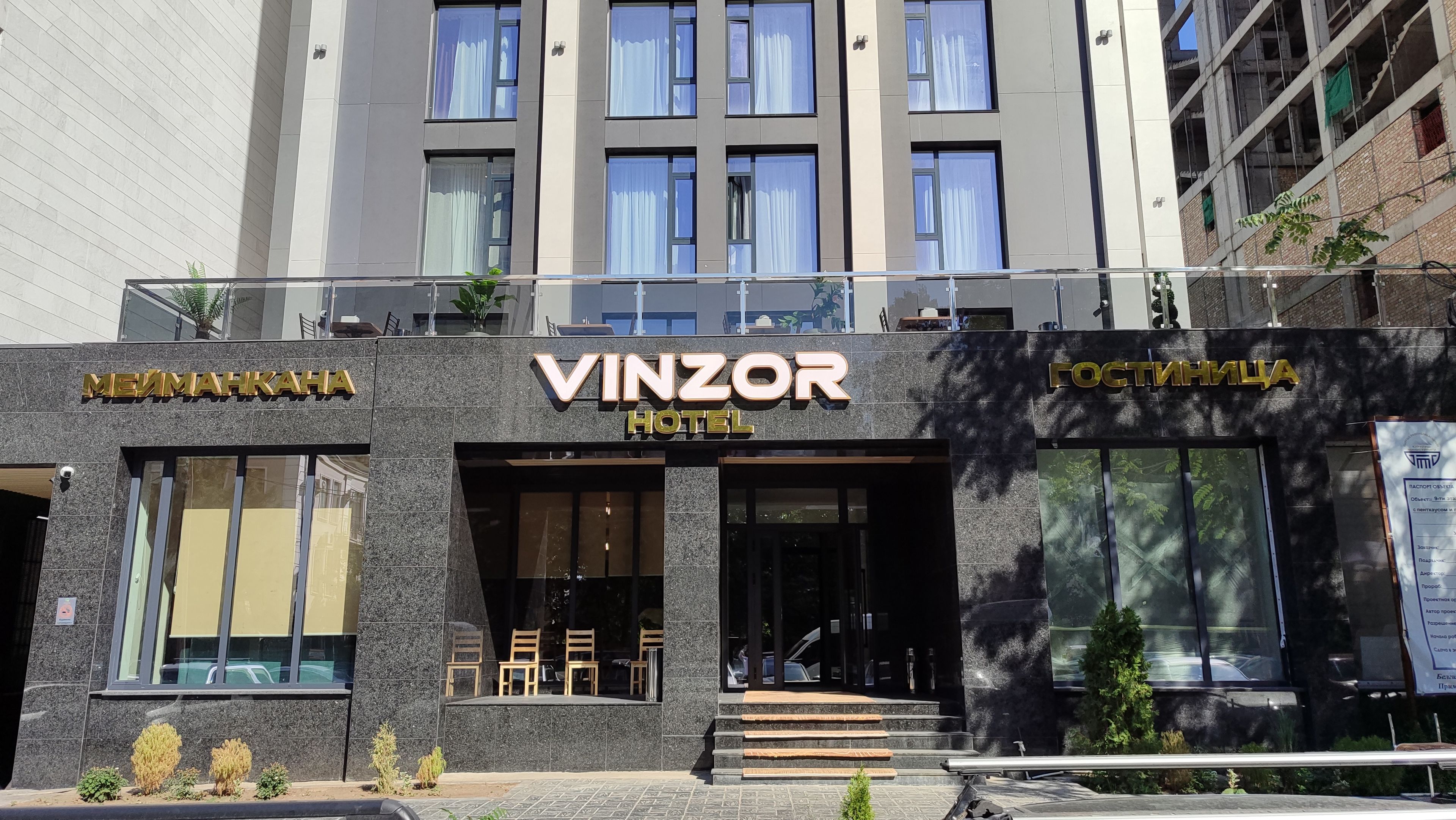 A hotel with a modern facade, large windows, and a sign that reads 'VINZOR HOTEL'.