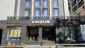 A hotel with a modern facade, large windows, and a sign that reads 'VINZOR HOTEL'.