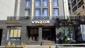 A hotel with a modern facade, large windows, and a sign that reads 'VINZOR HOTEL'. - Vinzor (Bishkek)