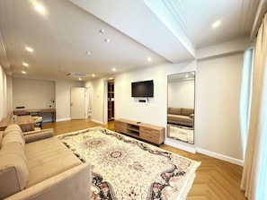 A modern living room with a large sofa, a flat-screen TV, a wooden coffee table, and a patterned rug. - Vinzor (Bishkek)