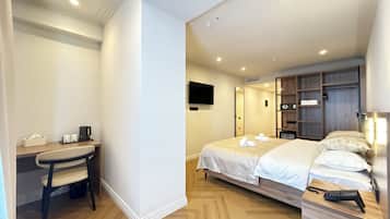 Habitación de hotel con cama, mesita de noche, escritorio, silla y televisión montada en la pared.