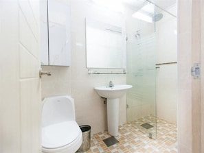 Un baño con inodoro, lavamanos y cabina de ducha de vidrio.