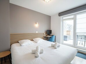 Ein Hotelzimmer mit einem großen Bett, einem Schreibtisch, einem Sessel und einem Fernseher.