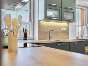 A modern kitchen with a wooden countertop, stainless steel appliances, and a window with a view.