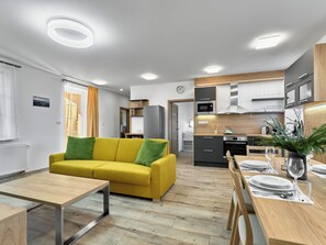 A modern kitchen with a dining area, a sofa, and a table set for a meal.