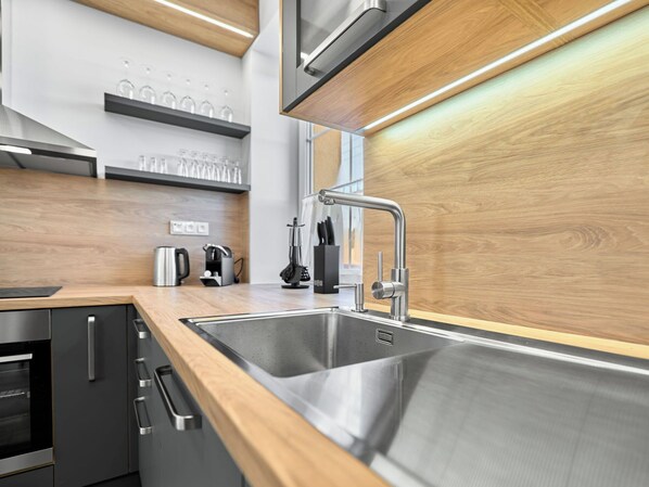 Una cocina moderna con electrodomésticos de acero inoxidable, armarios de madera y un lavamanos doble.