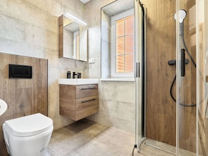 Un baño moderno con inodoro, tocador y ducha.