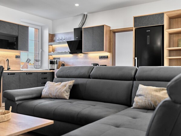 Una sala moderna con sofá, mesa de centro y cocina equipada, además de una mesa de comedor.