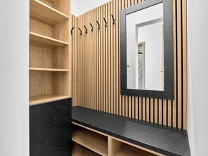 Ein modernes Badezimmer mit Holzlamellen, einer schwarzen Arbeitsplatte und einem Spiegel.