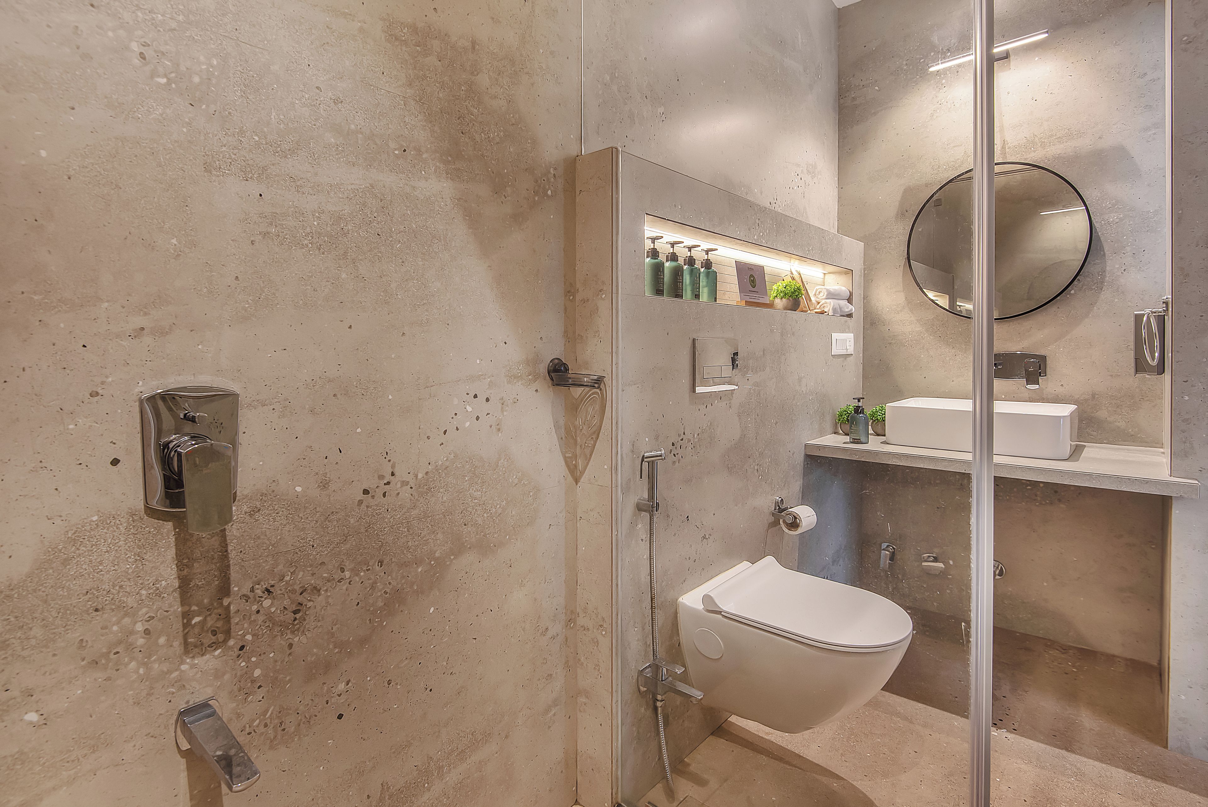 A modern bathroom with a glass-enclosed shower, a toilet, and a sink with a mirror above.