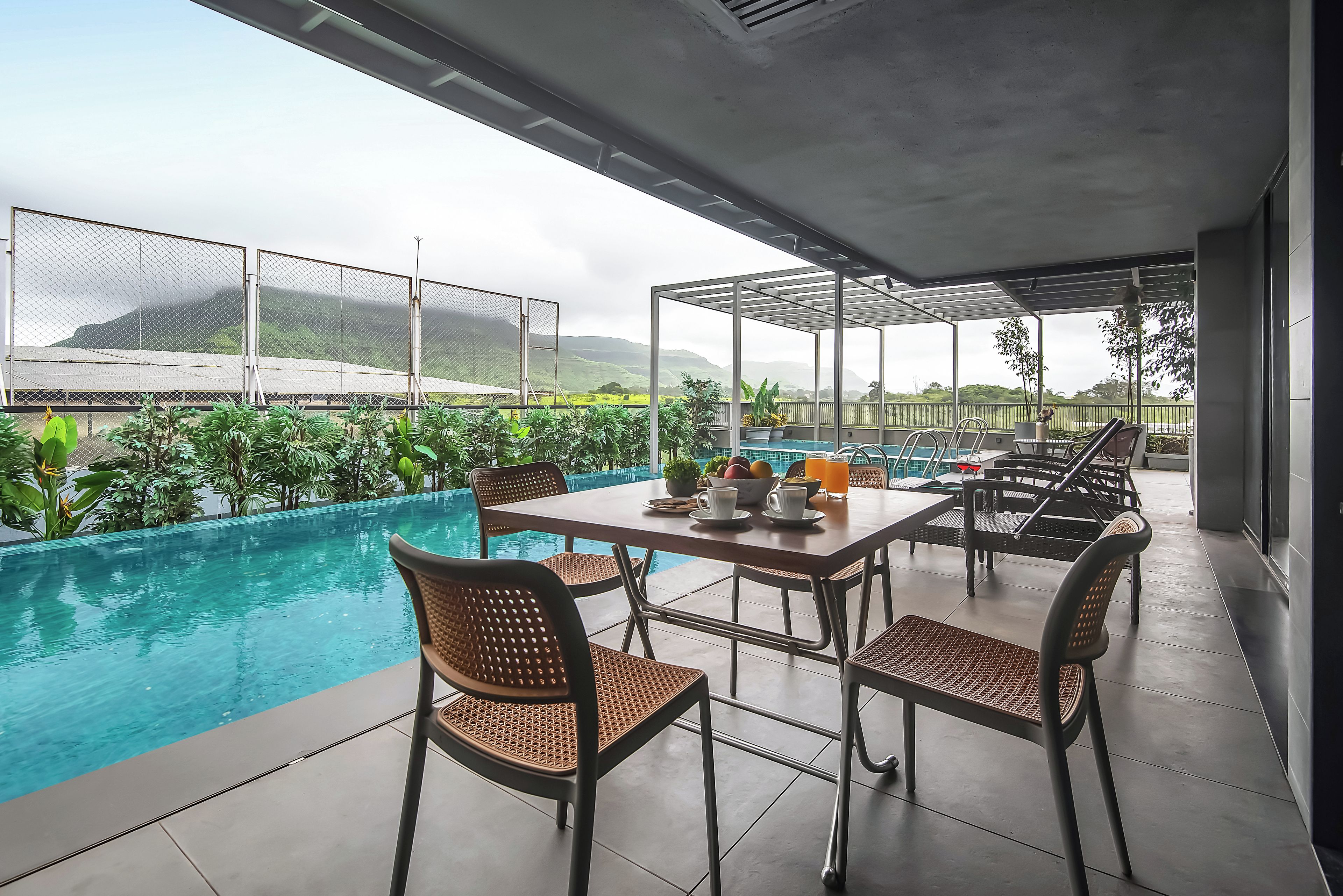 Un área junto a la piscina con mesa y sillas, una piscina y vistas a un paisaje montañoso.