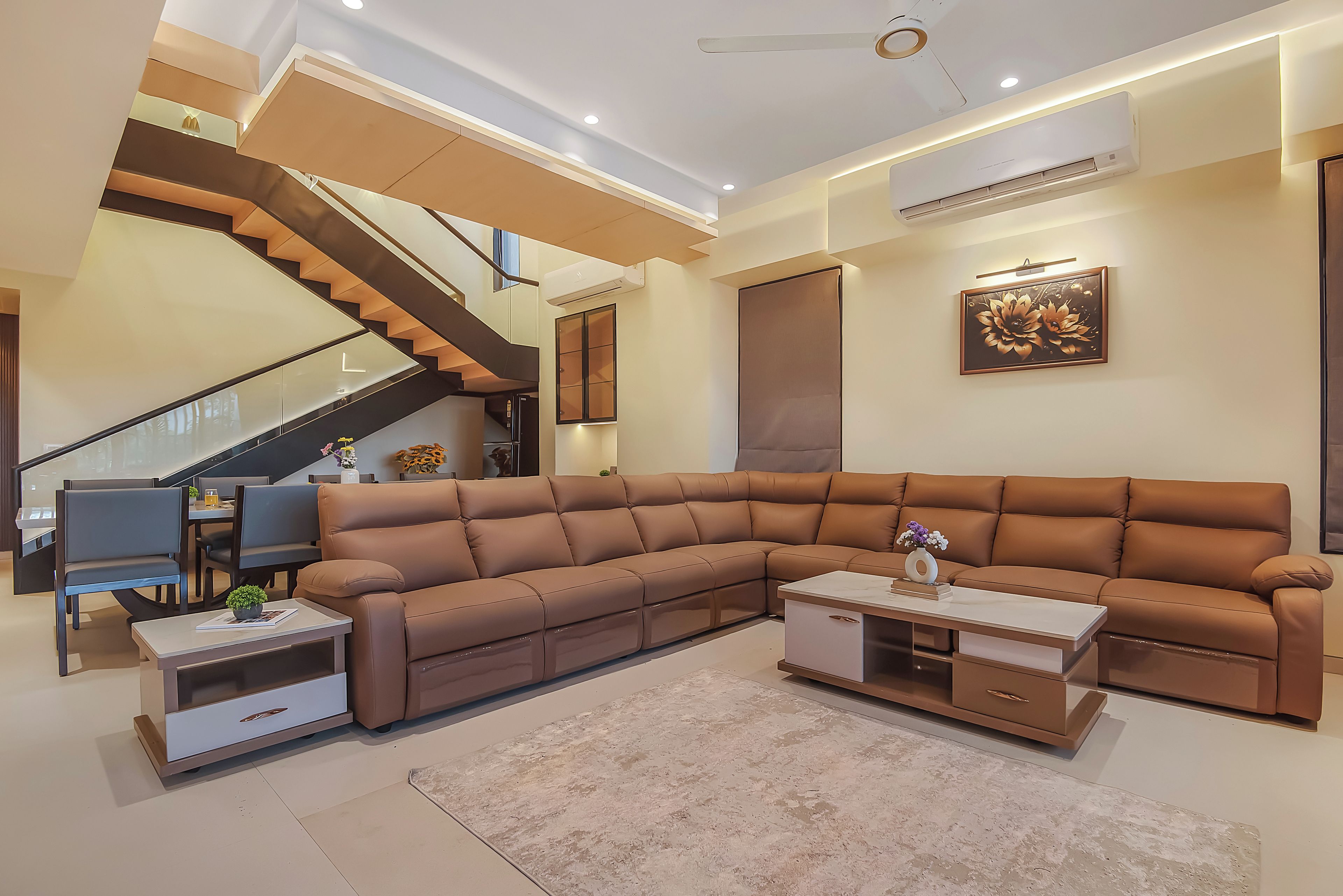 Ein modernes Wohnzimmer mit einer Eckcouch, einem Essbereich und einer Treppe.