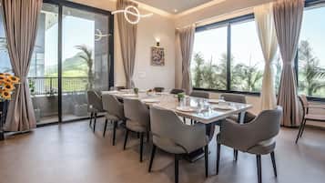 Un comedor con una mesa grande dispuesta para seis personas, rodeada de sillas, y vistas a la vegetación exterior.