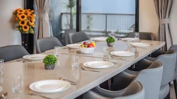 A dining table set with plates, cutlery, and a bowl of fruit.