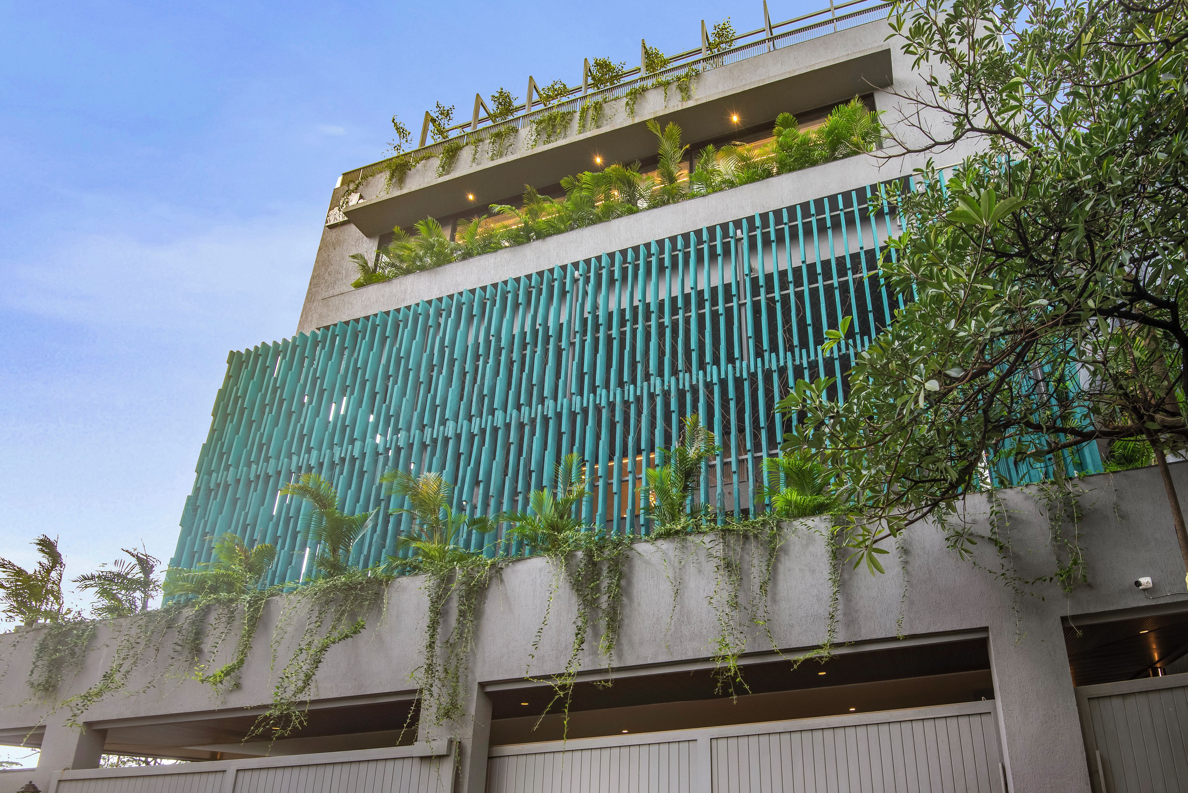 Un edificio moderno con fachada de vidrio, jardín vertical y techo plano con barandilla.