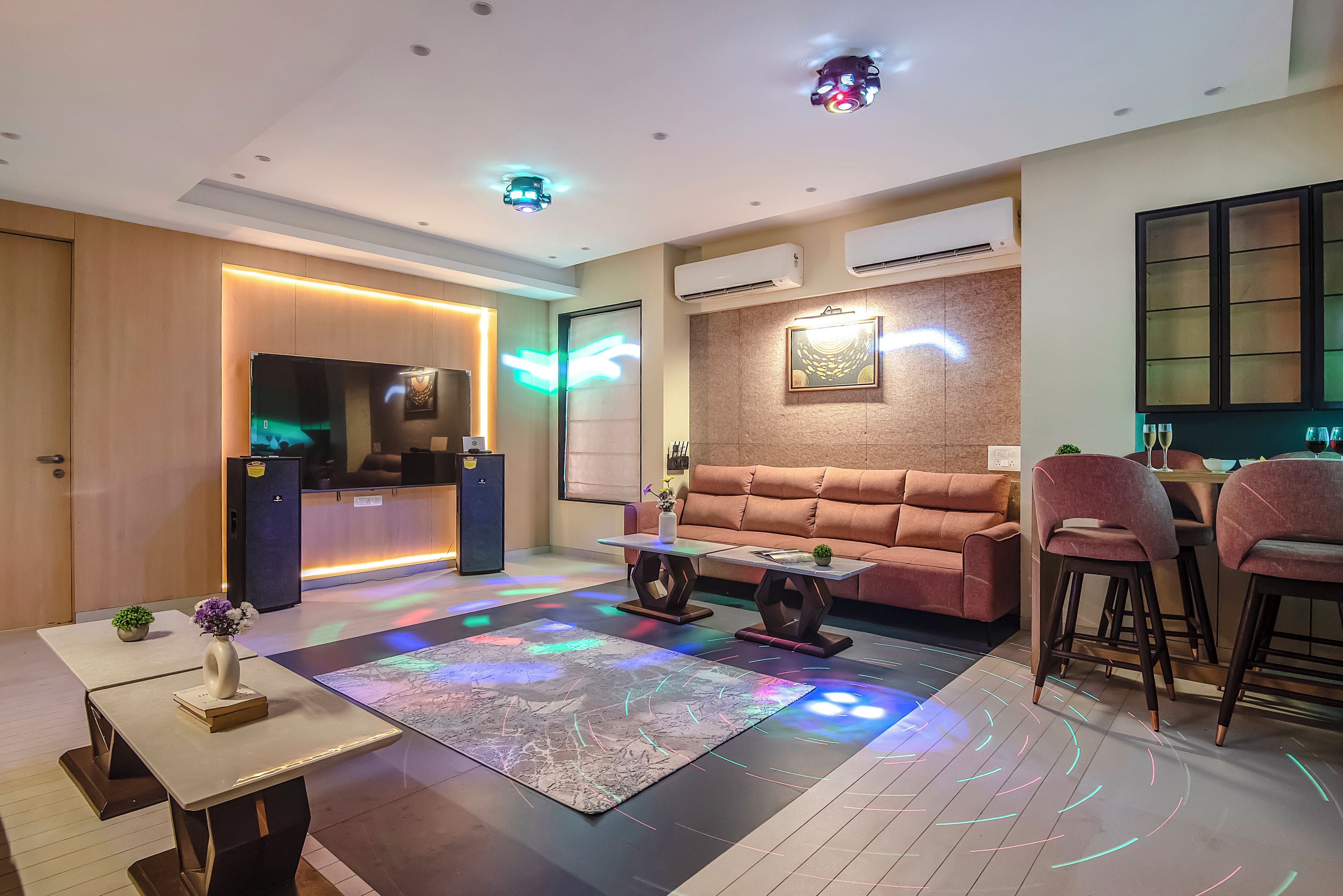 A modern living room with a sofa, a coffee table, a TV, and a bar area with stools.