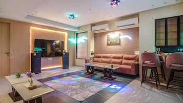 A modern living room with a sofa, a coffee table, a TV, and a bar area with stools.