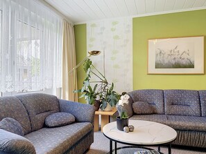 Een woonkamer met twee gestreepte banken, een ronde salontafel en een potplant.