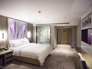 A hotel room with a bed, bedside table, and a television. - Lavande Hotels (Harbin)