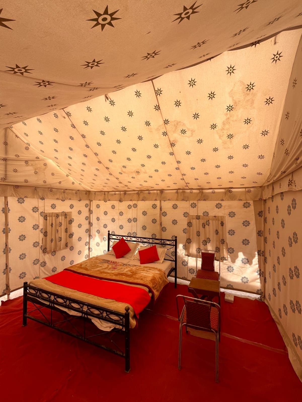 A tent-style room with a bed, a chair, and patterned walls.