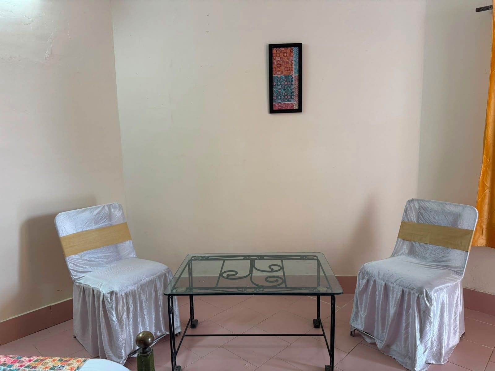 A room with two chairs, a glass-top table, and a framed artwork on the wall.