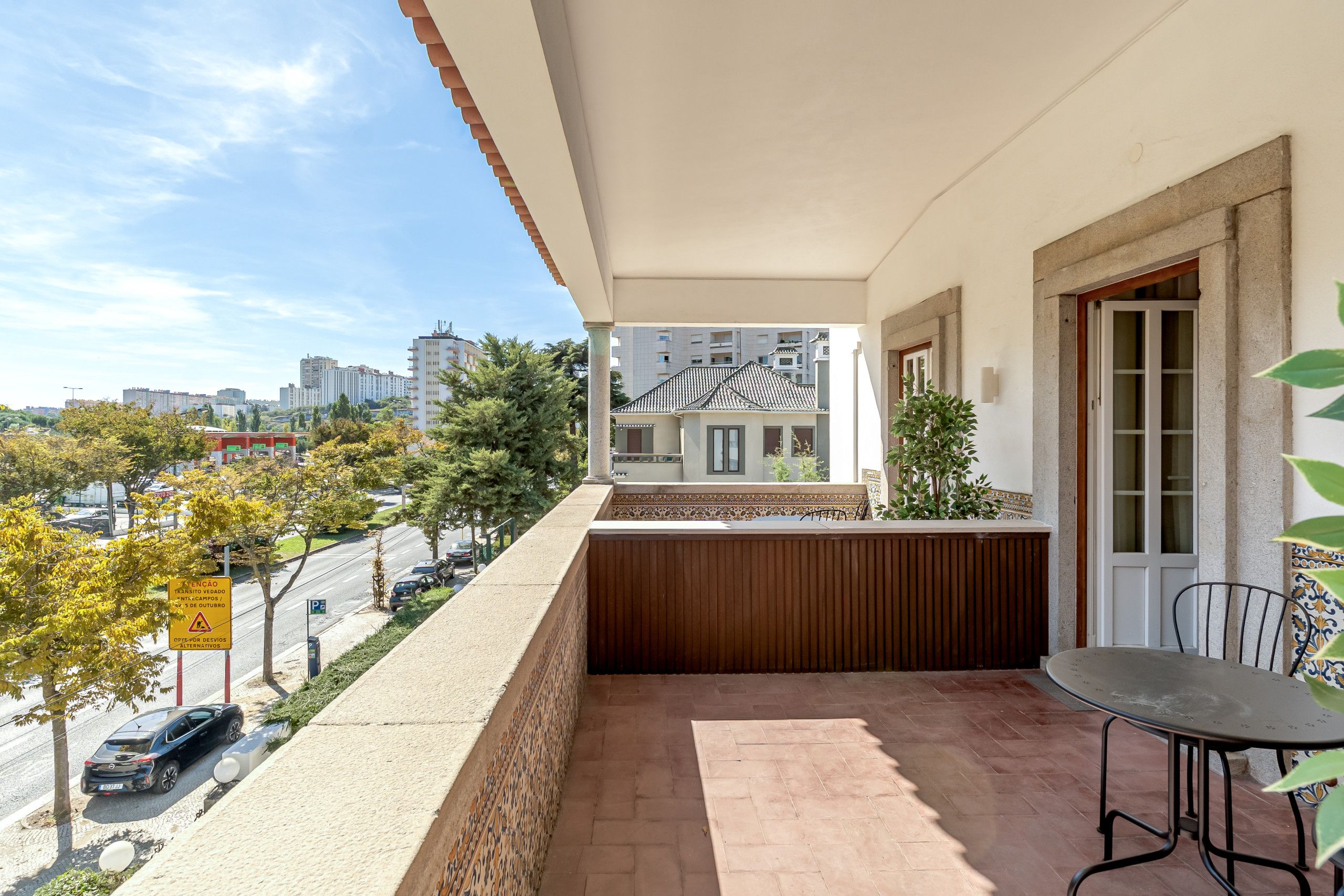 A balcony with a view of the cityscape, a table, and chairs.