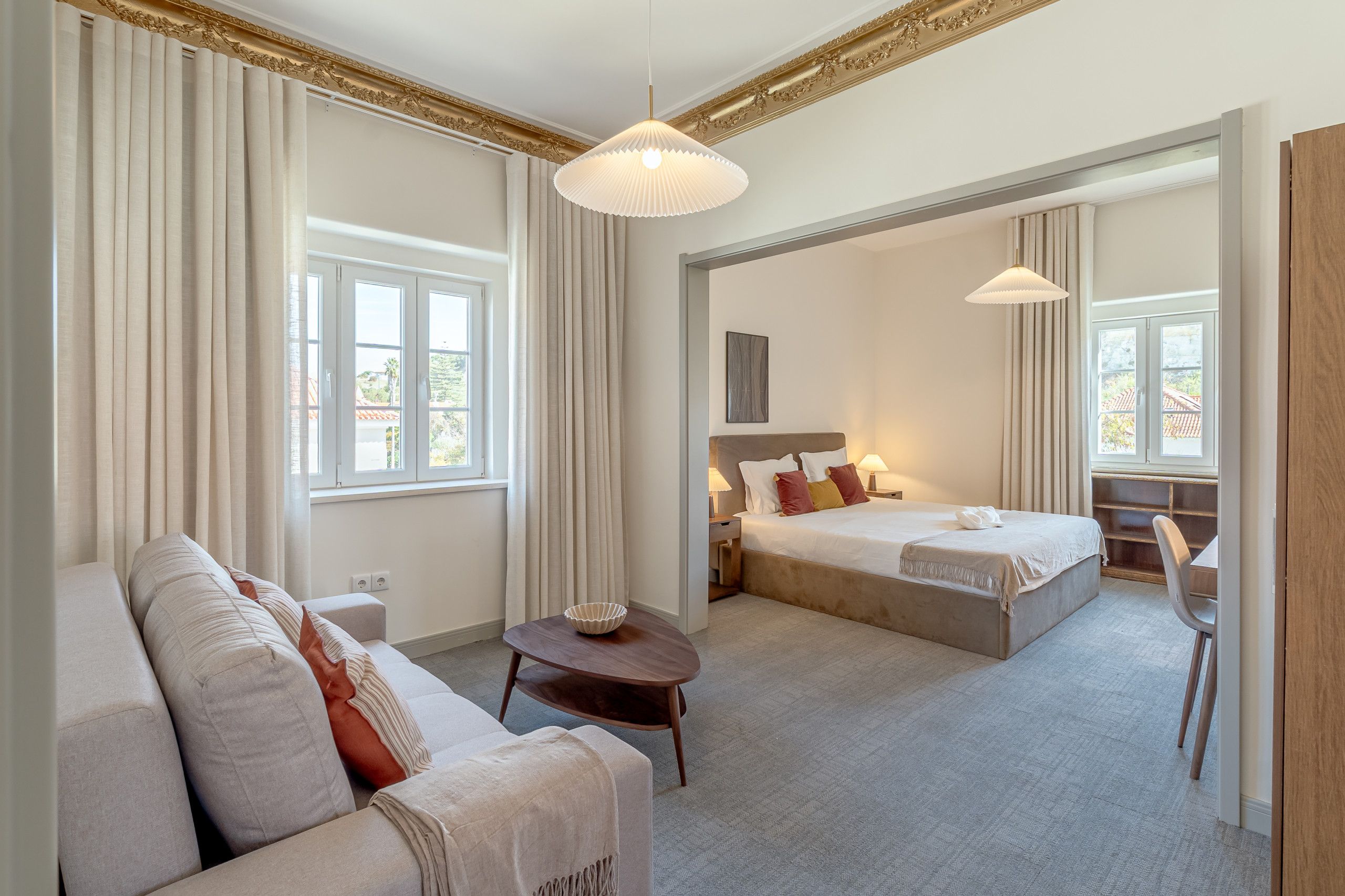 A hotel room with a sofa, a bed, a small table, and a chair.