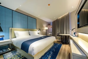 Una habitación de hotel con una cama grande, mesitas de noche, un escritorio, una silla, un televisor y una cortina.