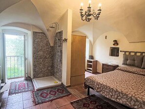 Ein Schlafzimmer mit einem großen Bett, einer Dusche und einem Balkon mit Blick.