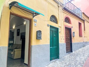 Ein Gebäude mit nummerierten Türen, einer grünen Tür und einem Balkon mit Geländer.