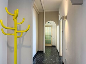 Ein Flur mit einem gelben Kleiderhaken, einer Tür mit satinierten Glasscheiben und einer Leuchte.